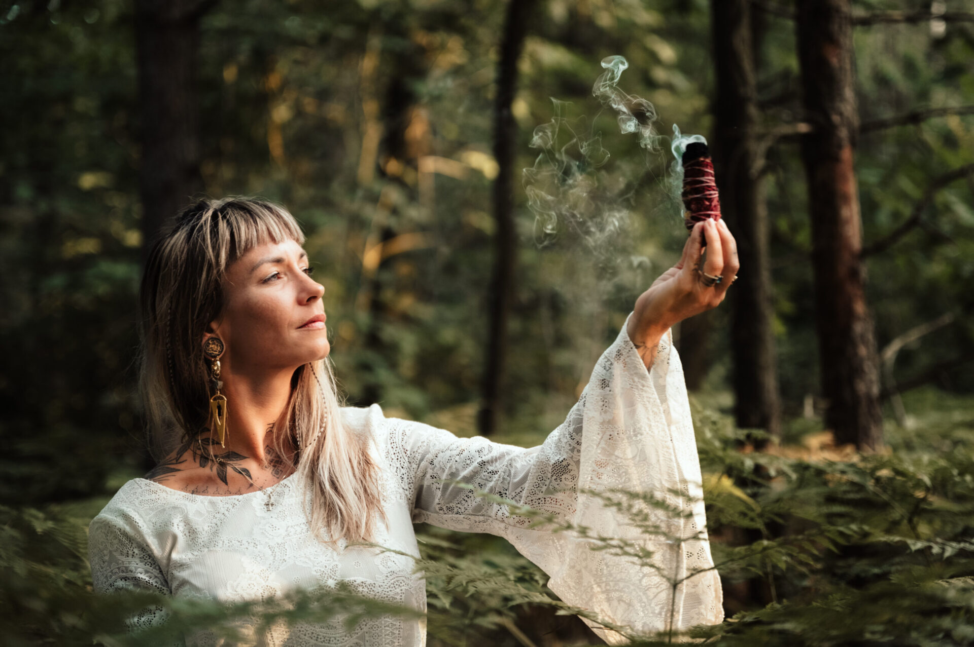 Frau mit Räucherstab im Wald.